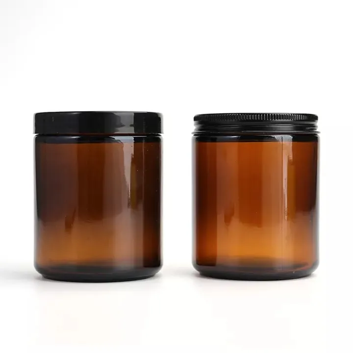 Two amber cylindrical glass jars with black flat and threaded lids