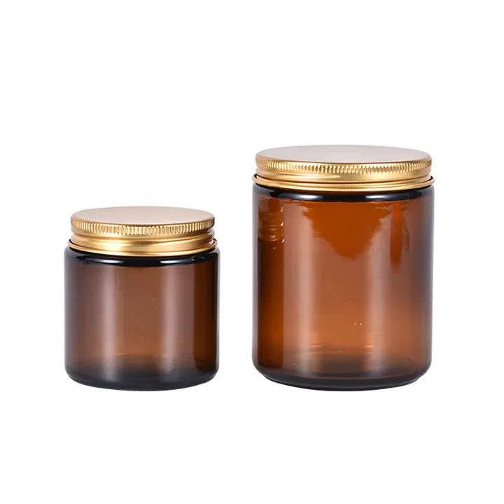 Two amber glass candle jars with gold metal lids