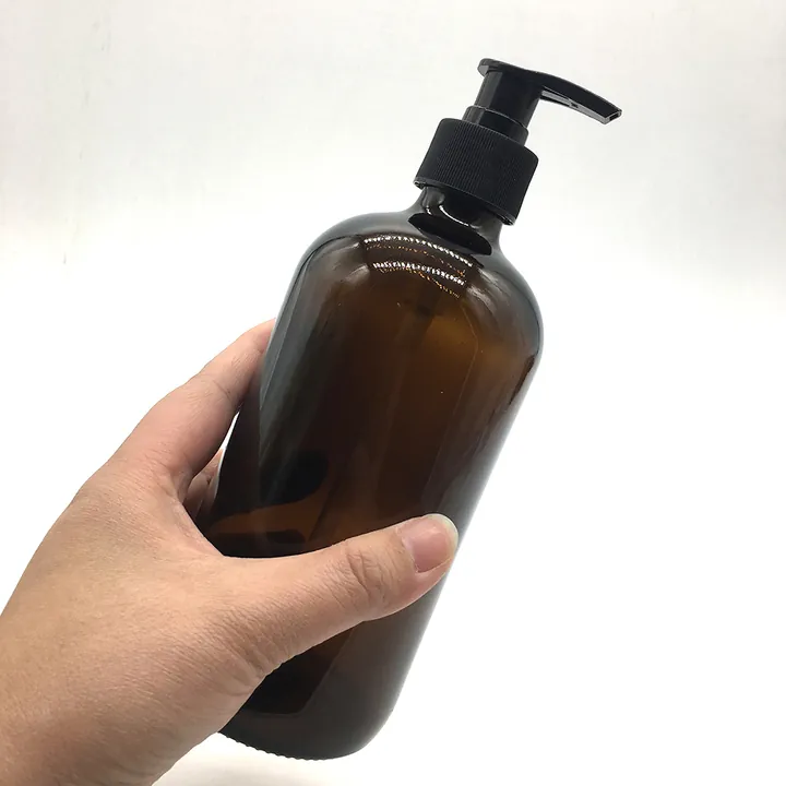 Mano que sujeta un frasco con bomba de cristal ámbar