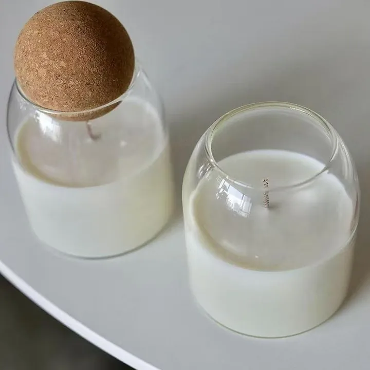 Glass jar with cork ball lid containing white candle