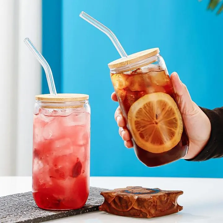 Two glass cups with bamboo lids and straws in a drink scene