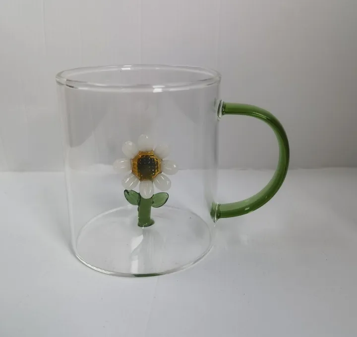 Glass mug with green handle and daisy decoration