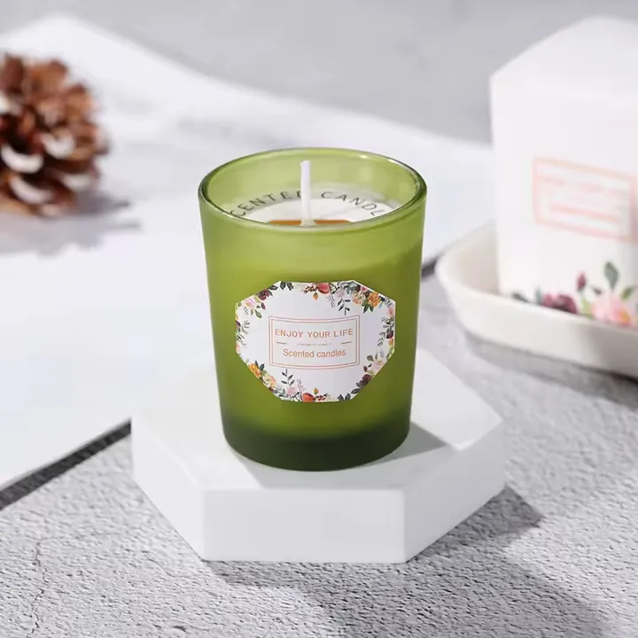Green glass candle jar with front label and lit candle in home fragrance setting