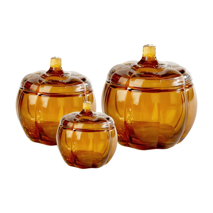 Three amber pumpkin shaped candle jars with matching lids