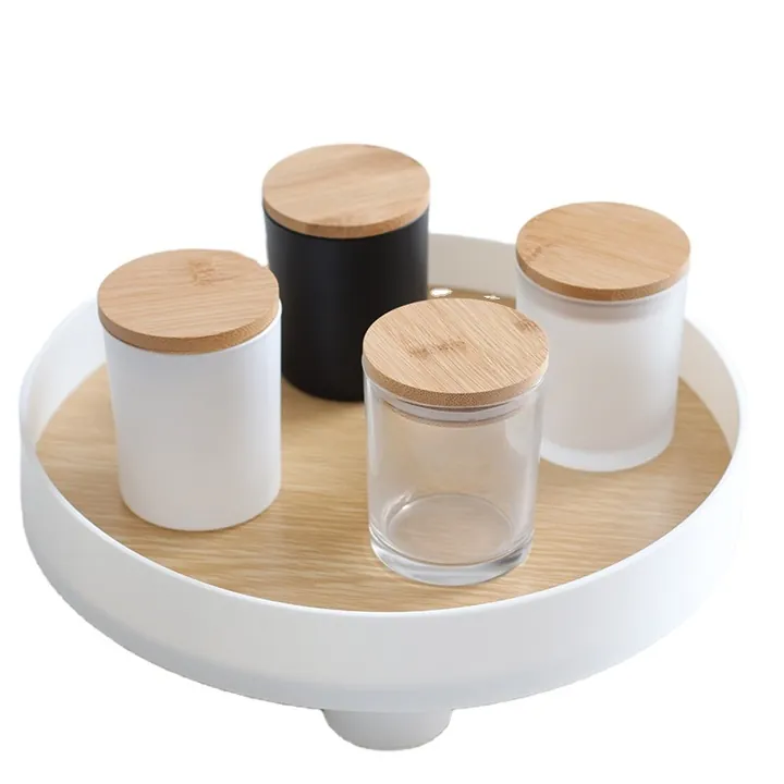 White black and clear candle jars with wooden lids on a tray