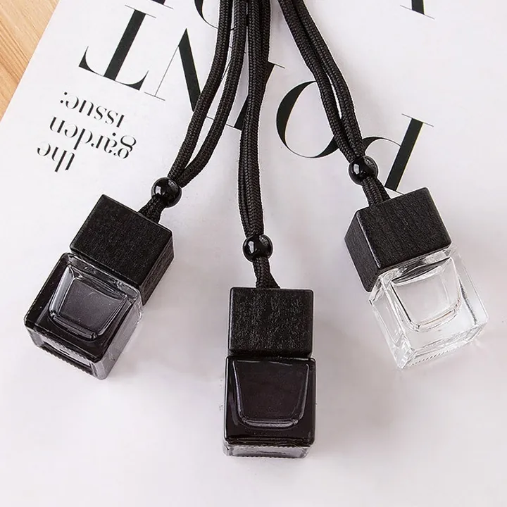Three square car diffuser bottles with black wooden caps and hanging cords