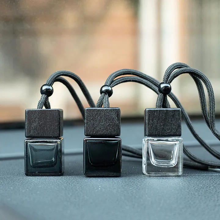 Three square car diffuser bottles with black wooden caps and cords