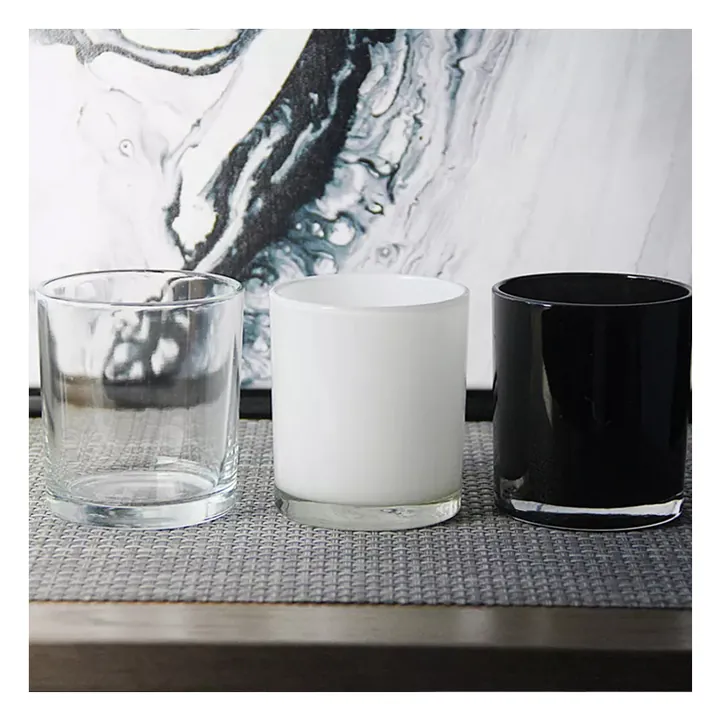 Clear white and black glass candle jars on marble background