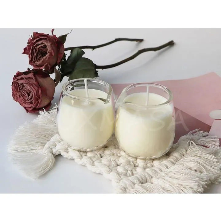 Two clear glass candle jars with white candles and flowers