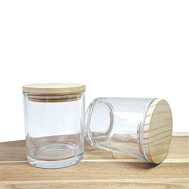 Two clear cylindrical glass candle jars with wooden lids