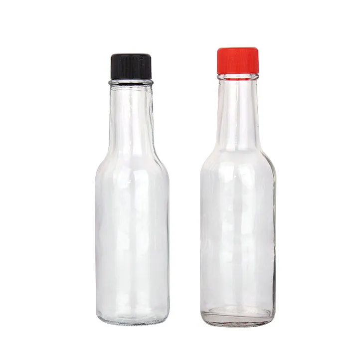 Zwei schlanke Soßenflaschen aus klarem Glas mit schwarzen und roten Verschlüssen