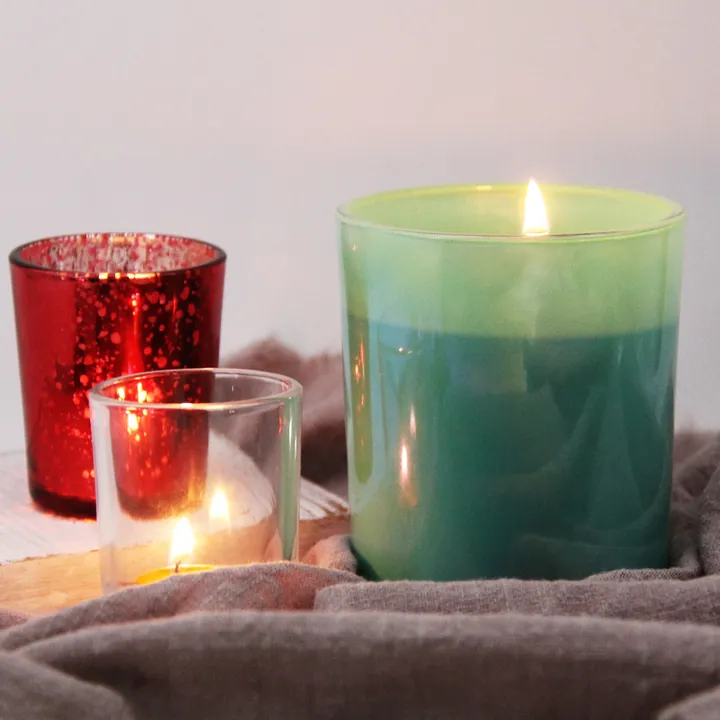 Green red and clear glass candle jars in a lit scene