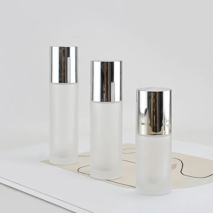 Three white frosted cylindrical cosmetic bottles with silver screw caps