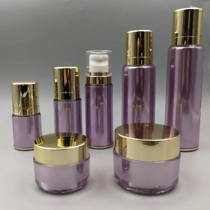Purple transparent cosmetic bottles and cream jars with gold caps