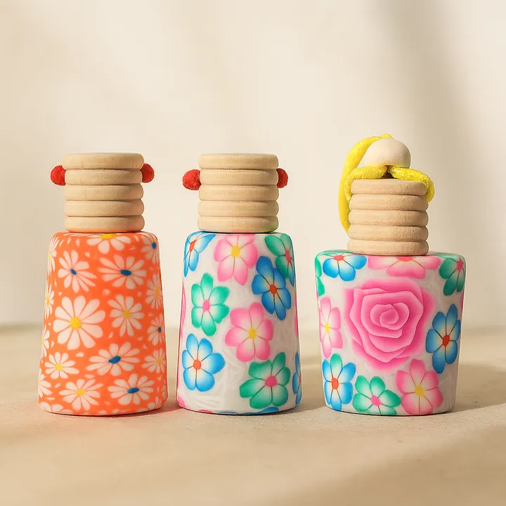 Three small colorful floral diffuser bottles with wood grain caps and hanging cords