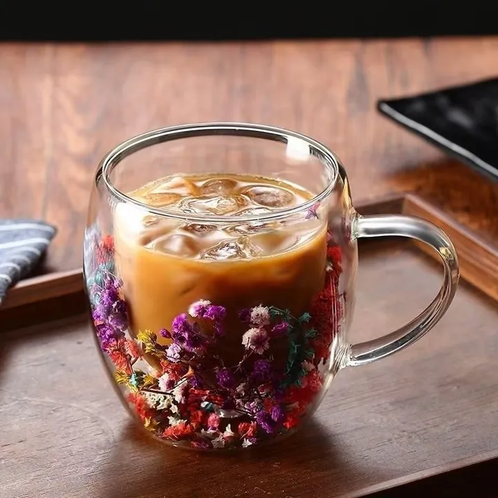 Double wall glass mug with dried flowers and iced coffee