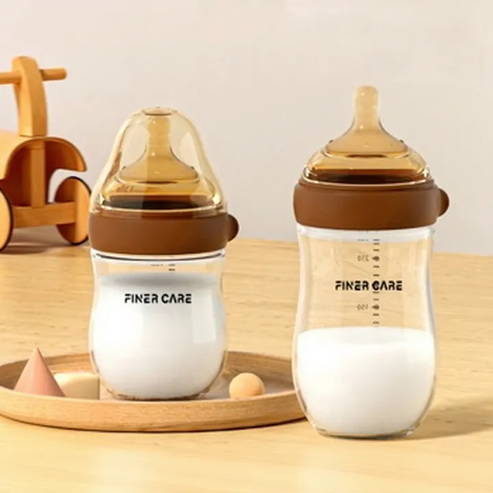 Two wide mouth glass baby bottles filled with milk on wooden tray