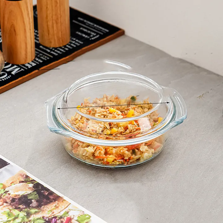Un saladier en verre avec couvercle, rempli de riz frit, posé sur un plan de travail de cuisine