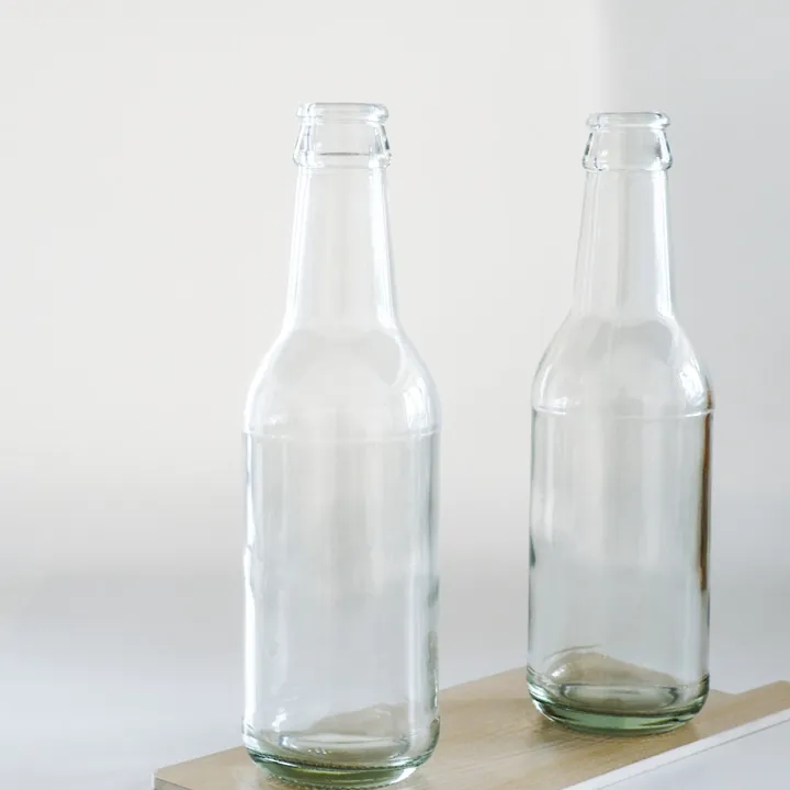 Two clear long neck beverage bottles displayed together