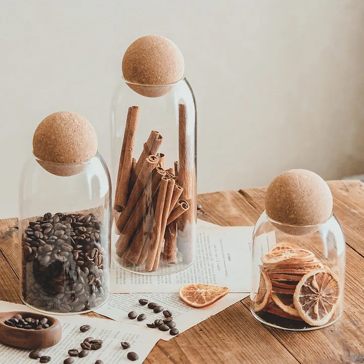 Three ball cork glass canisters filled with spices and pasta on a table