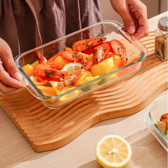 Un plat à gratin rectangulaire en verre rempli de crevettes et de légumes sur la table à manger