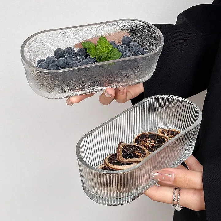 Deux coupes à fruits ovales en verre transparent, disposées à la main