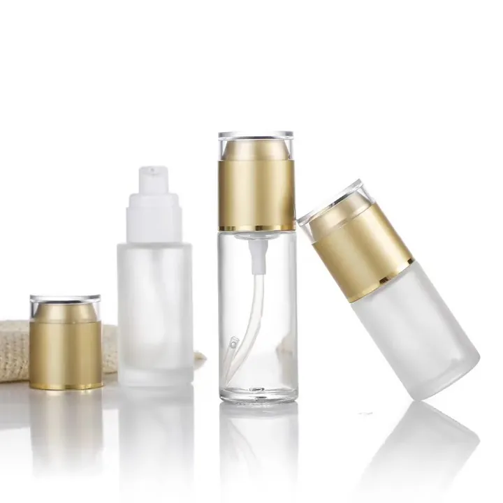 Frosted glass spray pump bottles with gold shoulders and clear outer caps