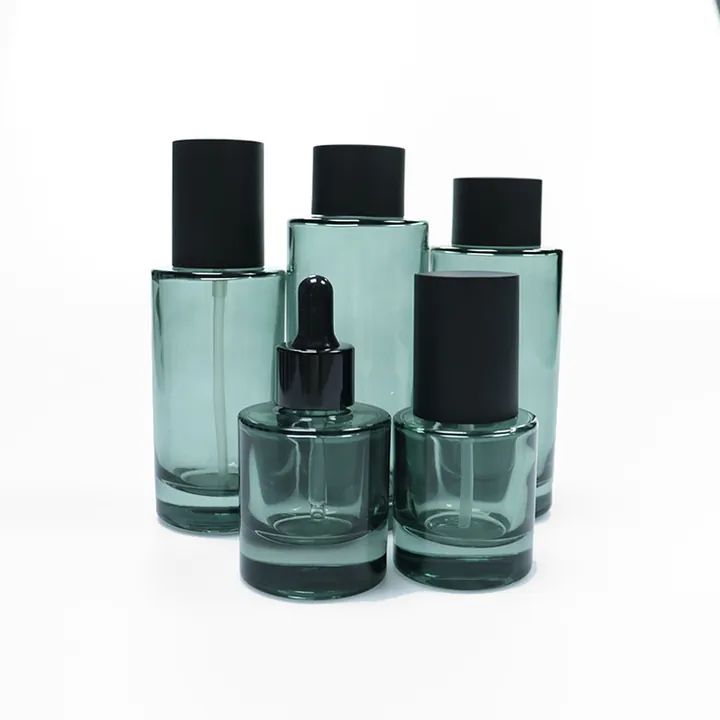 Deep green transparent glass skincare bottles and jars with black caps and droppers