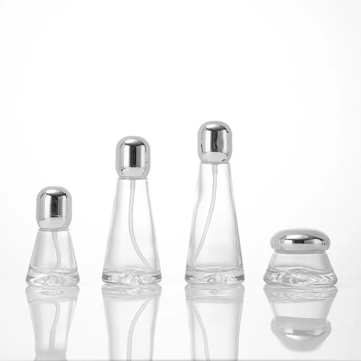 Clear tapered glass lotion bottle and cream jar with silver rounded caps