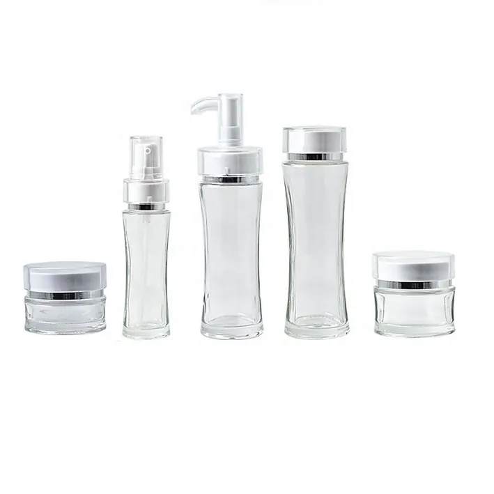 Clear waist-shaped glass skincare bottles and jars with white caps and silver rings