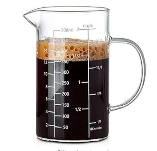 Glass measuring cup filled with coffee and scale markings