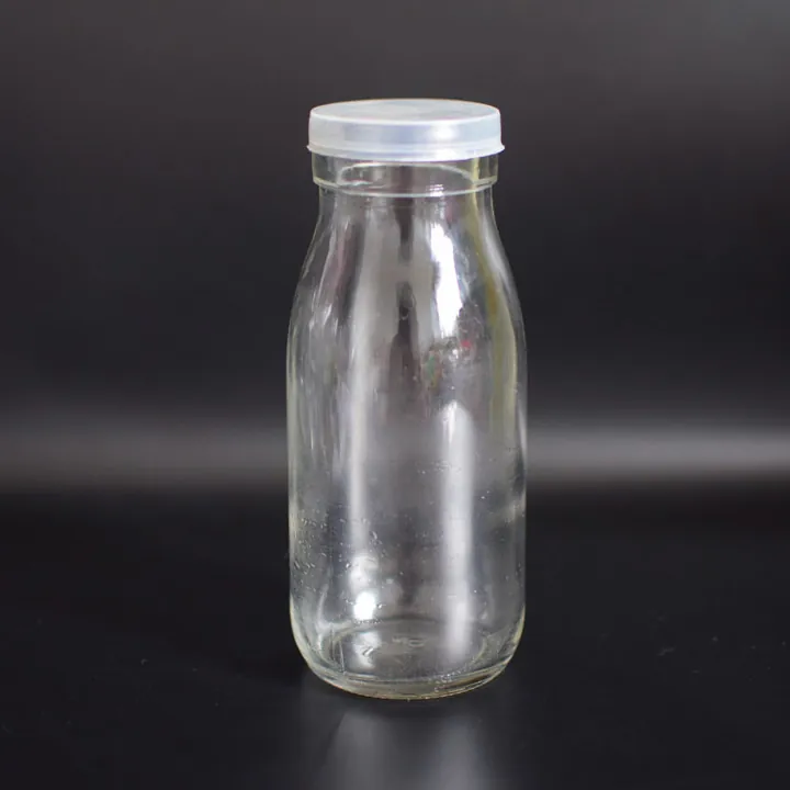 Milchflasche aus klarem Glas mit weißem Kunststoffverschluss