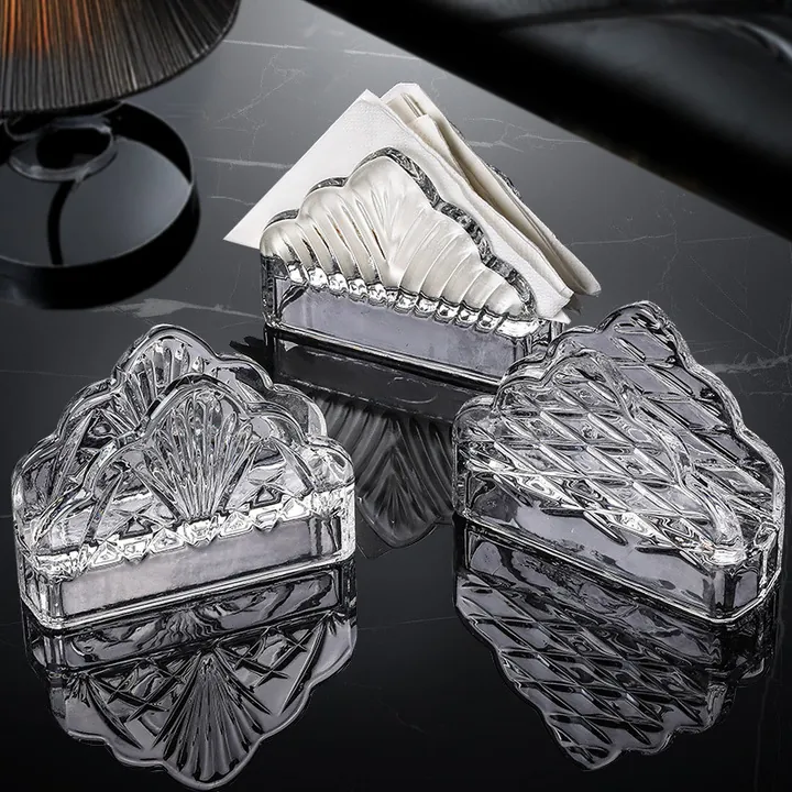 Trois porte-serviettes en verre transparent en forme d'éventail posés sur une table sombre