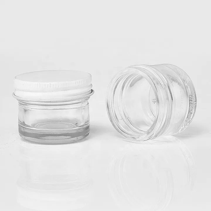 Small clear glass cream jars with white lids and open jar