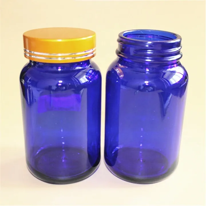 Two cobalt blue glass pill bottles with gold and black lids