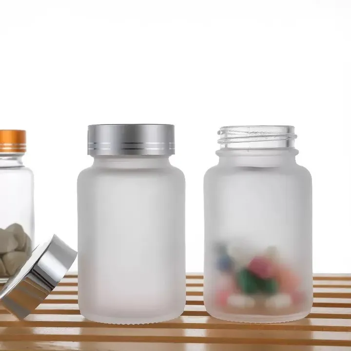 Frosted glass pill bottle with tablets and metal lid