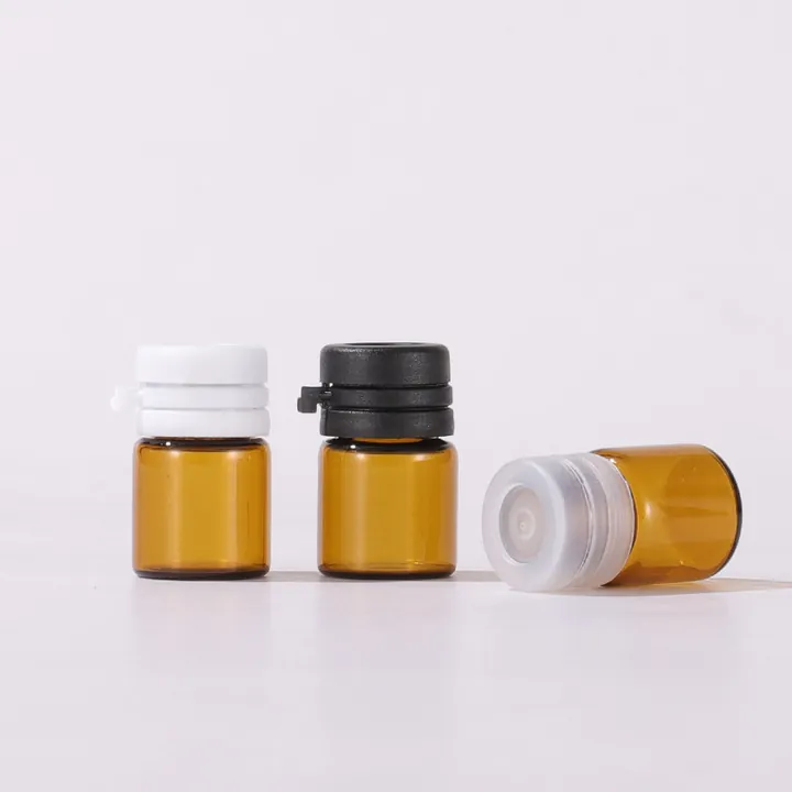 Three amber mini glass pill bottles with white and black caps