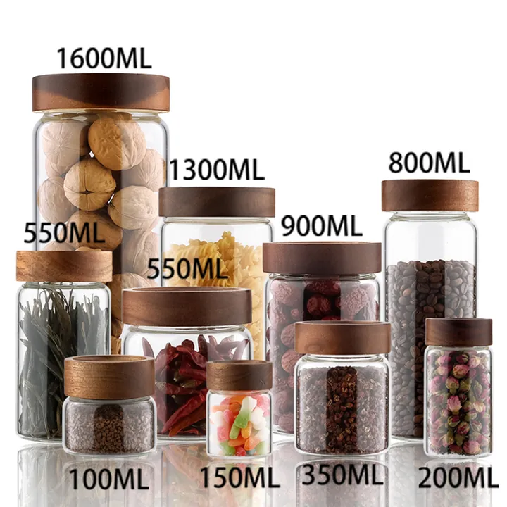 Clear glass storage jars with wooden lids holding nuts, coffee beans, spices and candy