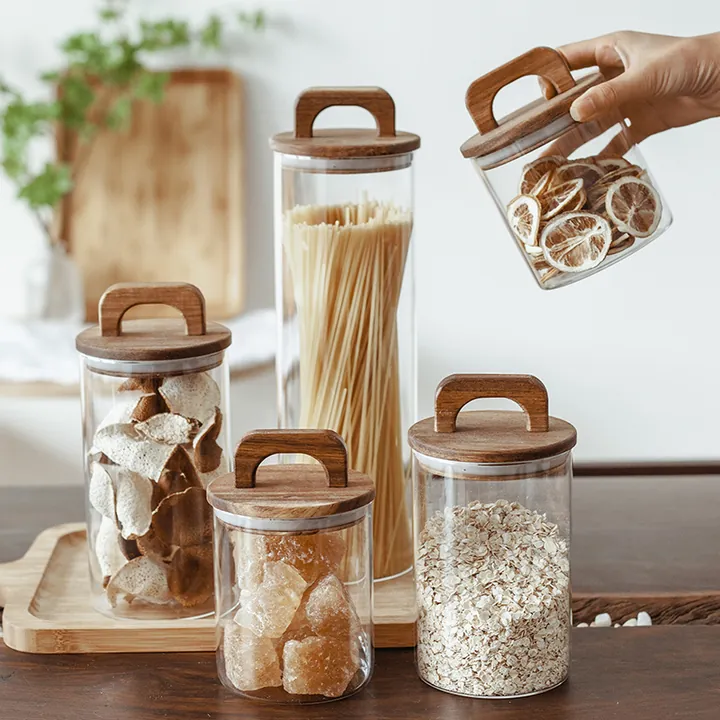 Cinq bocaux de conservation en verre transparent avec des couvercles en bois munis d'une poignée et des ingrédients