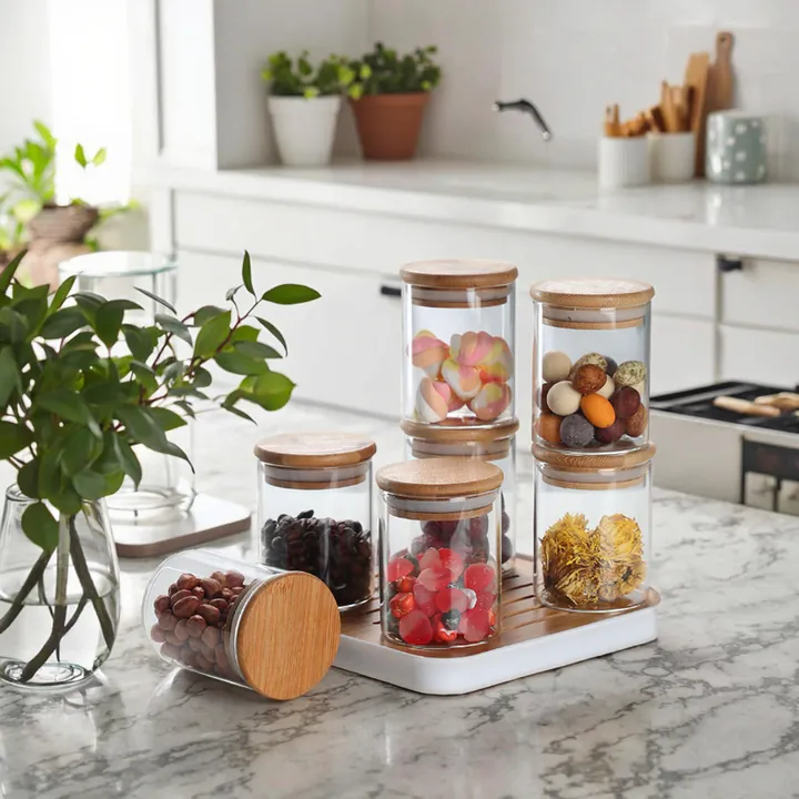 Des bocaux de conservation en verre transparent avec des couvercles en bambou et un plateau dans une cuisine