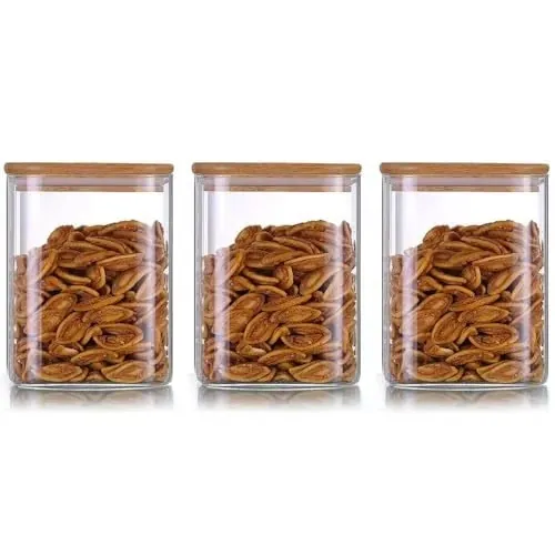 Trois bocaux de conservation carrés en verre transparent avec des couvercles en bambou et des snacks