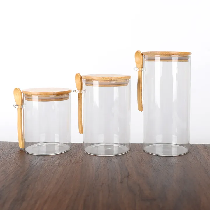 Trois bocaux de conservation en verre transparent avec des couvercles en bambou et des cuillères en bois à suspendre