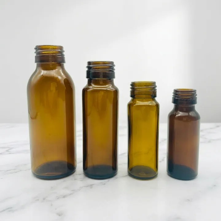 Four amber glass syrup bottles in different heights without caps