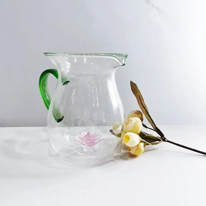 Théière en verre transparent avec une anse verte et un motif floral rose