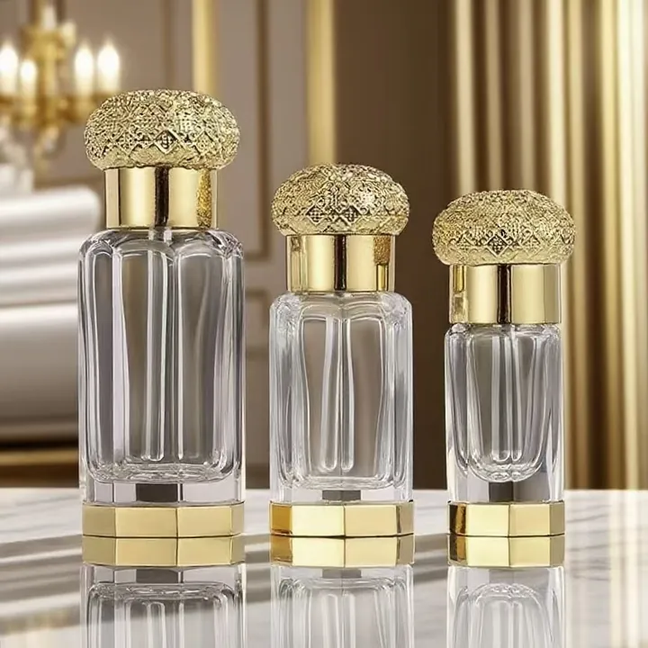 Trois flacons de parfum transparents, avec un socle doré et un bouchon en cristal gaufré