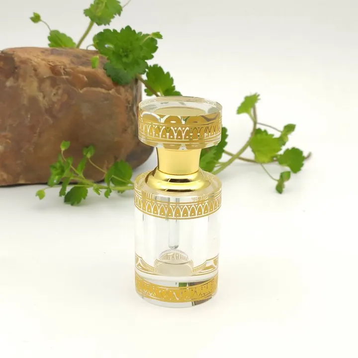 Clear cylindrical perfume bottle with gold decorative pattern on body and cap