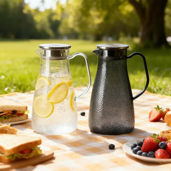 Wasserkrüge aus transparentem und rauchfarbenem Hammerschlagglas in einer Picknick-Kulisse im Freien