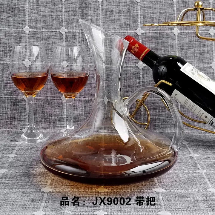 Transparente Weinkaraffe mit großem, rundem Henkel neben einem Weinglas und einer Flasche