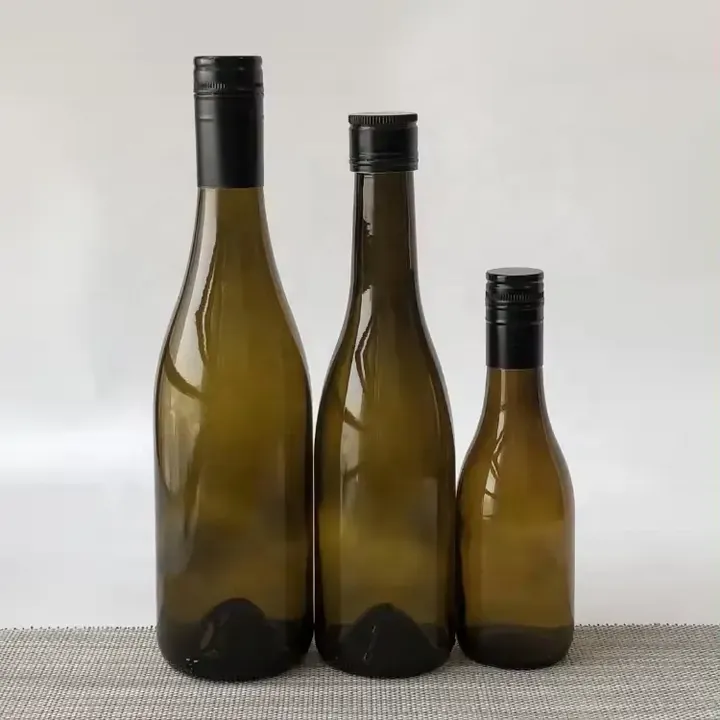 Tres botellas de vino de cuello largo de color ámbar, de diferentes alturas, con tapones negros
