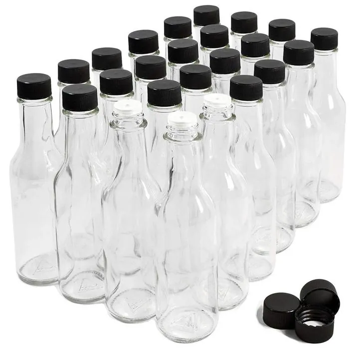 Multiple clear hot sauce bottles with black caps